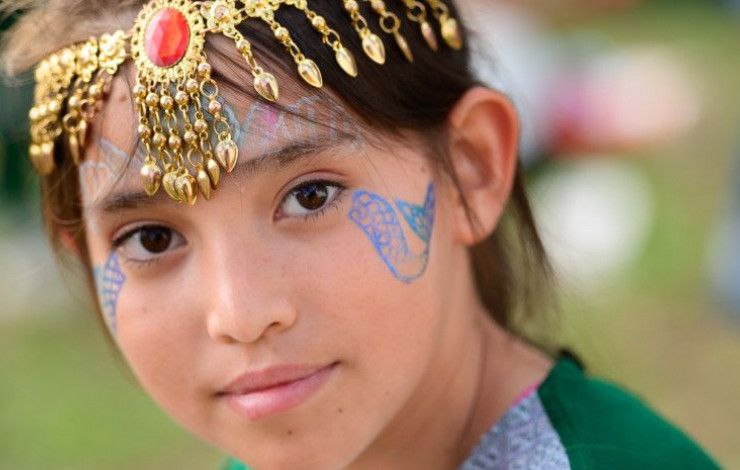 Young girl with headdress and mermaid tail face paint