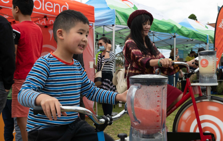 A child rides a bike to power a blender mixing a smoothie.