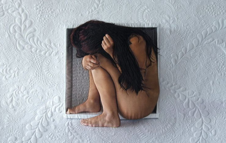 A woman crouched inside a hole in a white, textured wall.