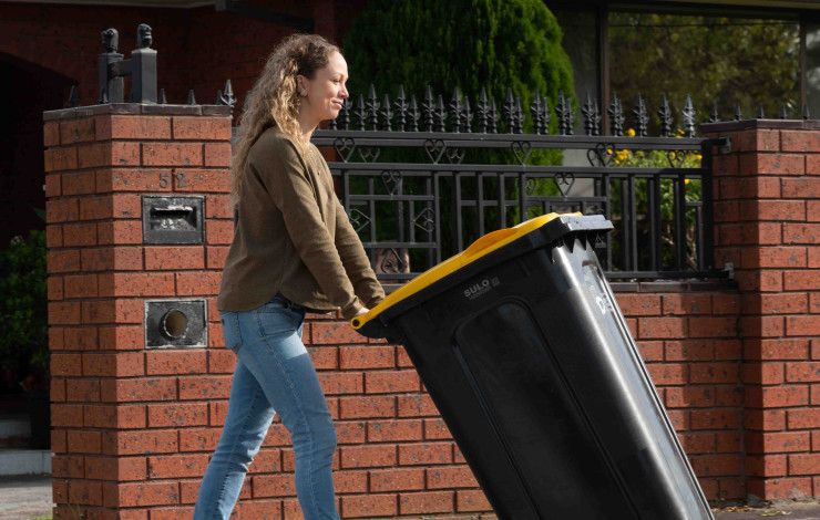 Resident pushing recycle bin out to the curb
