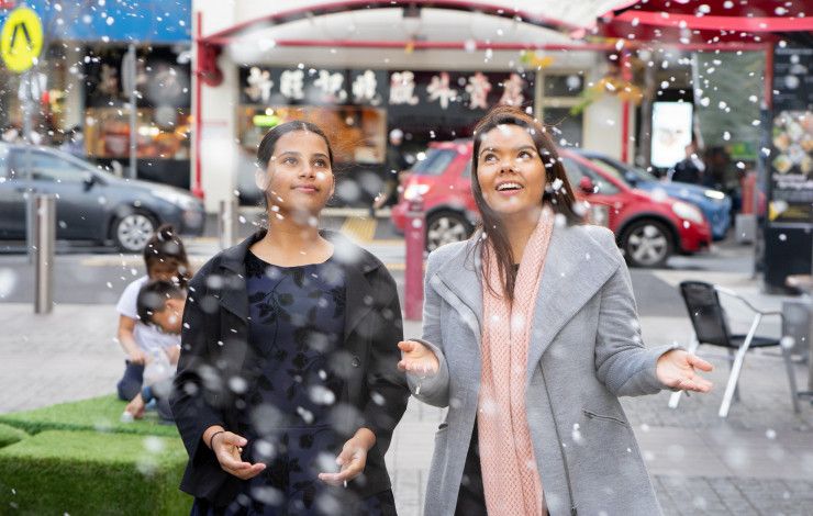 Junior Mayor Tasneem and Mayor Eden Foster stand next to each other as snow falls
