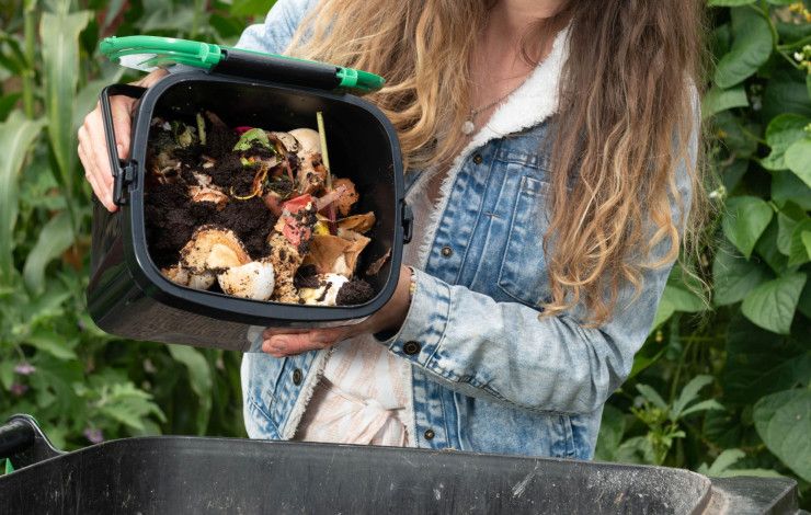 a person tipping compost into a large bin