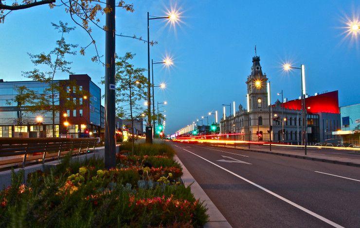 Looking down astreet at twilight with an historic clock tower and office buildings in the background