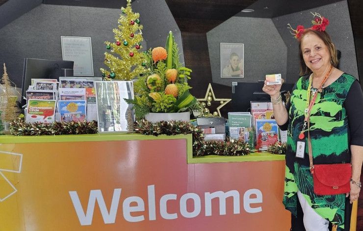 Staff member at the Dandenong Library service desk holding a membership card.