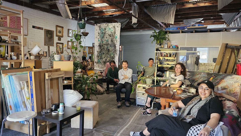 Five people sitting on different chairs inside an art studio.