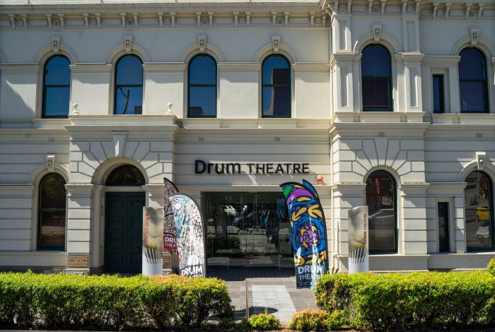 View of the facade of The Drum theatre with plants and flags.