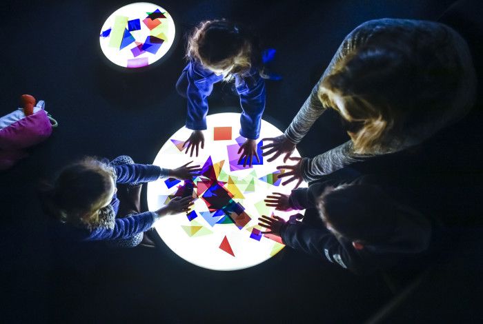 Family playing with paper shapes on light up circle.