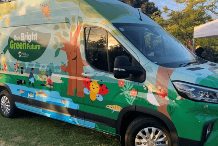 A green van covered with illustrations of trees, people and wildlife.