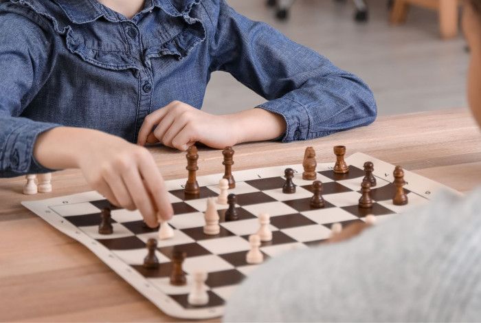 A girl and a boy sitting at a table playing chess