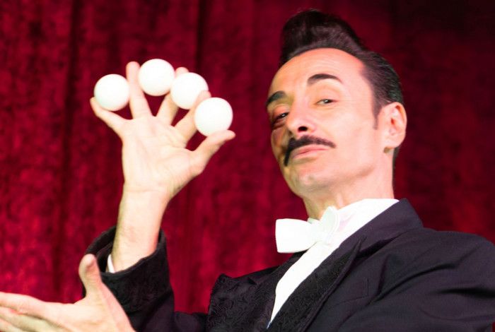 Magician holding four small white balls in his hand