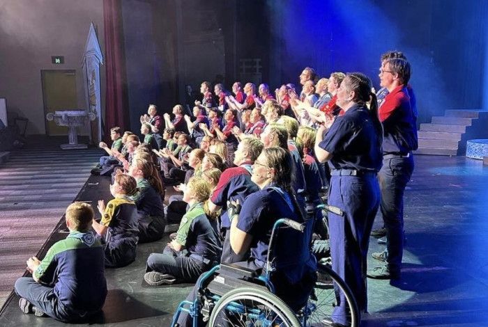 Large group of children and several adults assembled on a stage