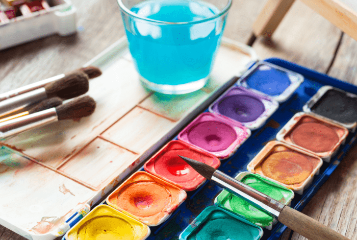 A watercolour paint set with paint brushes on a table