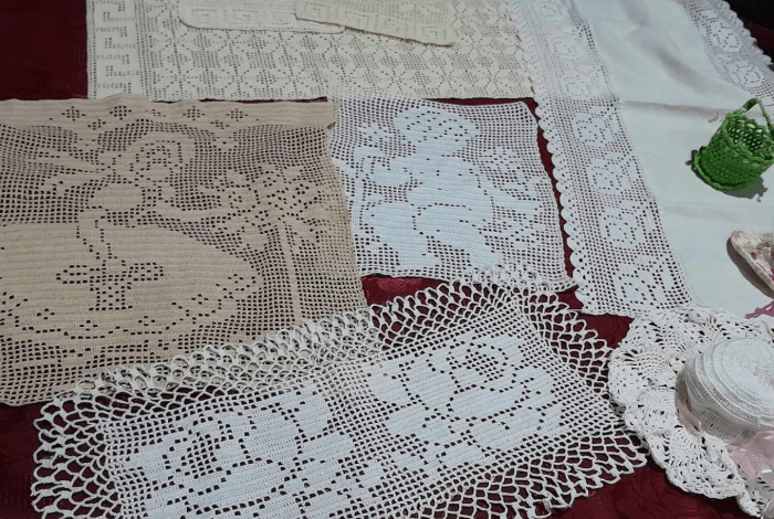 Table covered in crochet placemats and hats.