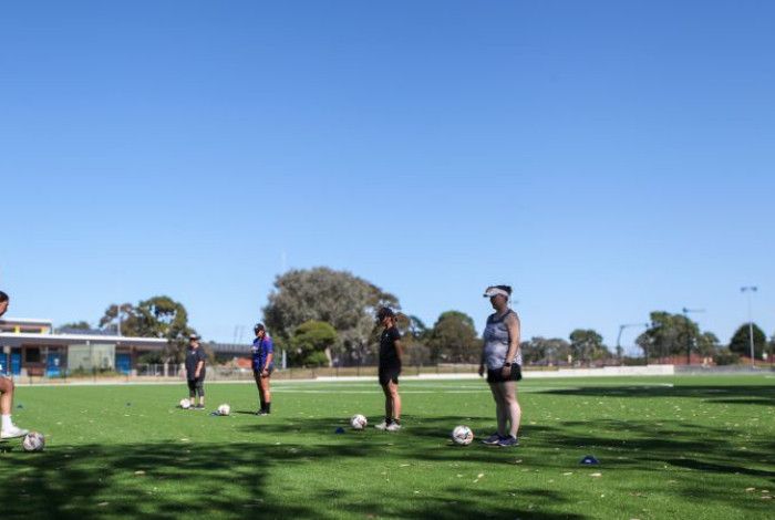 Women standing with soccer balls at their feet