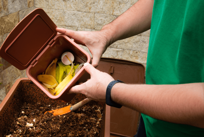 Person adding scraps to compost pile.