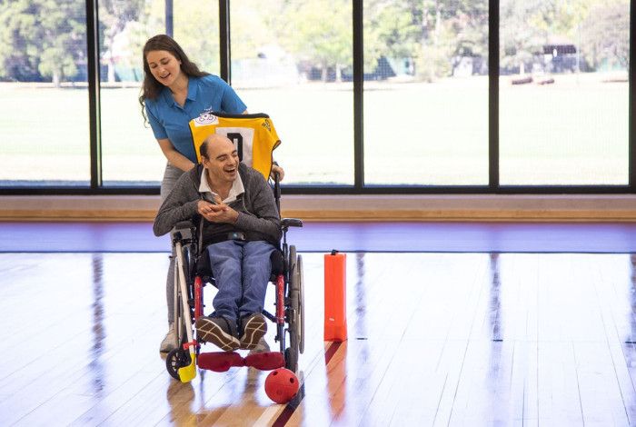 Person in a wheelchair playing hockey with support staff