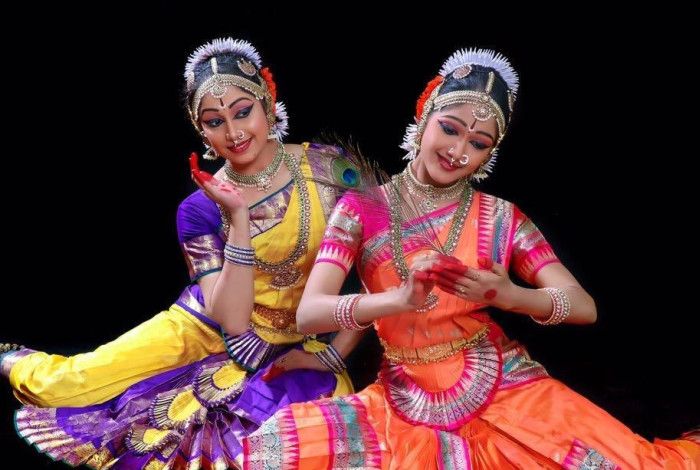 Two women in colourful, traditional dress, striking elegant poses