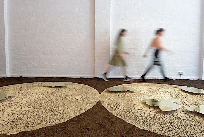 Two figures walk behind a flat rendering of a world map