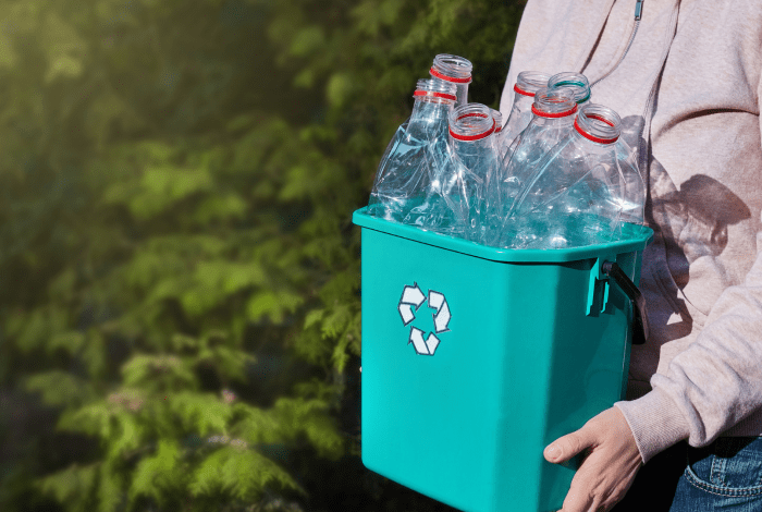 Person holding a bucket filled with plastic bottles