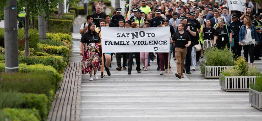 A crowd walks behind the Walk Against Family Violence banner