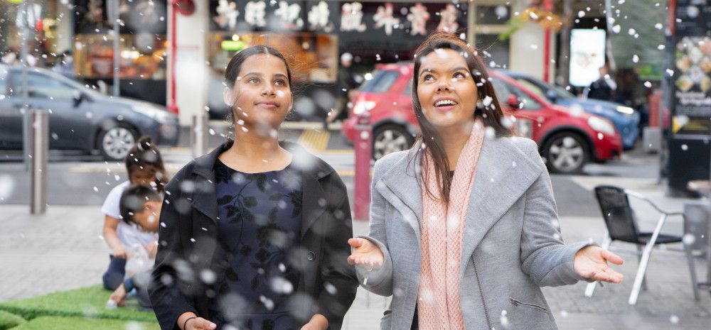 Junior Mayor Tasneem and Mayor Eden Foster stand next to each other as snow falls