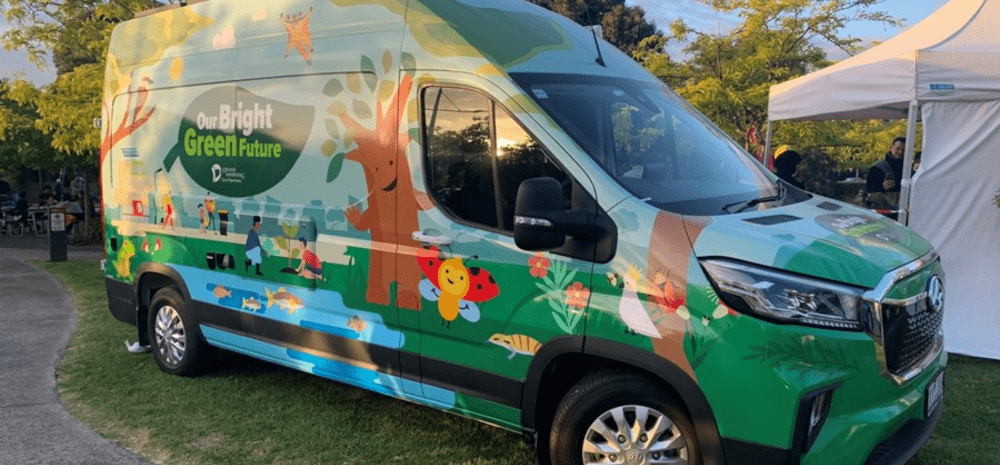 A green van covered in illustrations of trees, people and wildlife.
