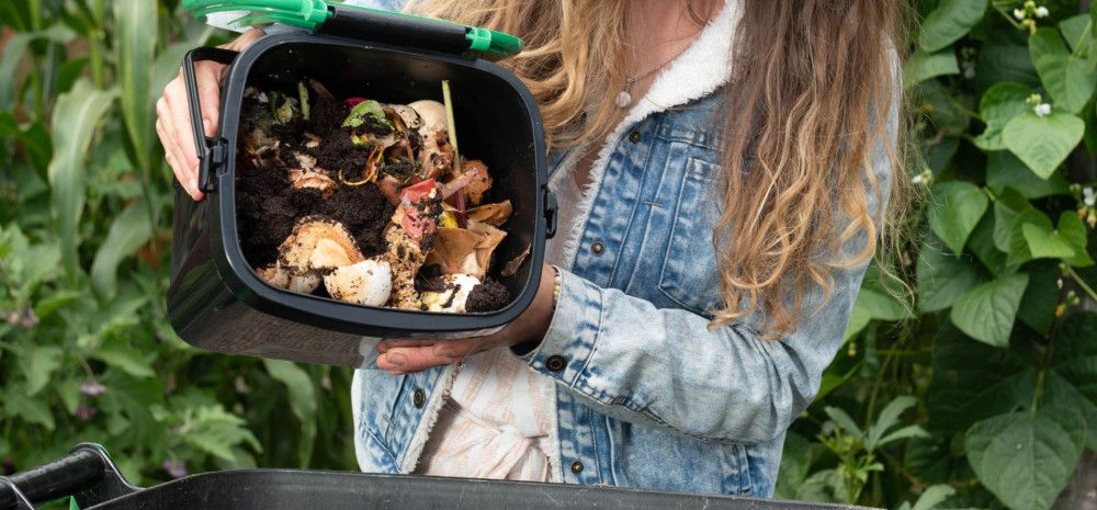 a person tipping compost into a large bin