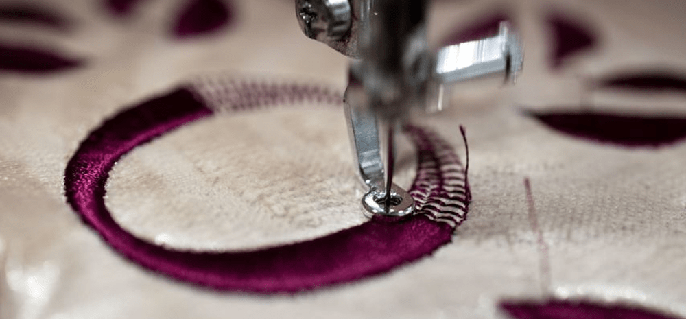 embroidery machine sewing a letter with burgundy thread