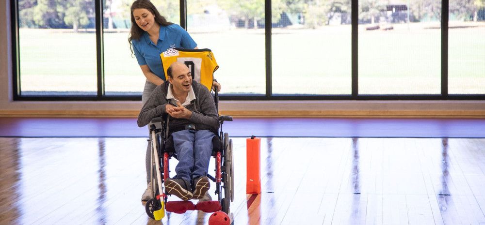 Person in a wheelchair playing hockey with support staff