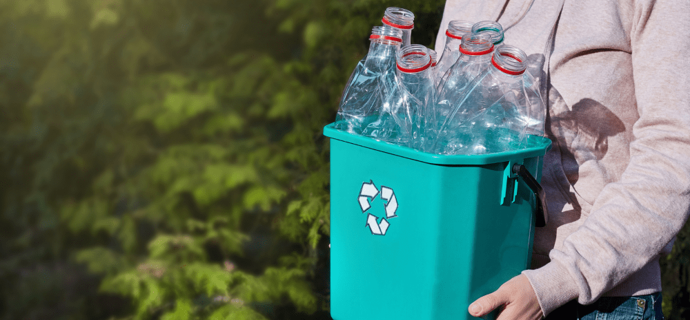 Person holding a bucket filled with plastic bottles