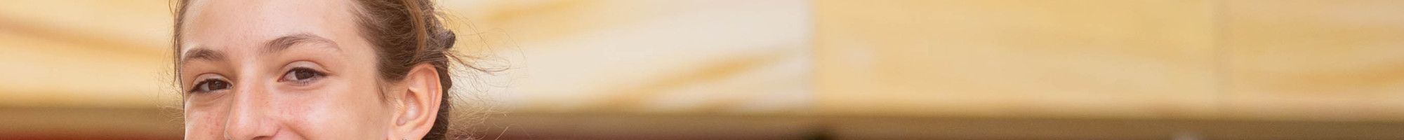 A girl dressed in blue robes smiles at the camera while standing side on