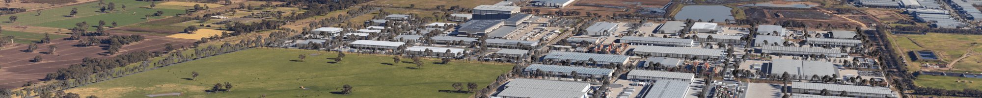 A view from above of a large suburb including housing, an industrial estate and open green paddocks