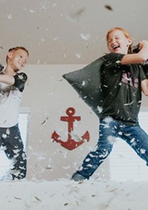 Kids jumping on a bed pillow fighting